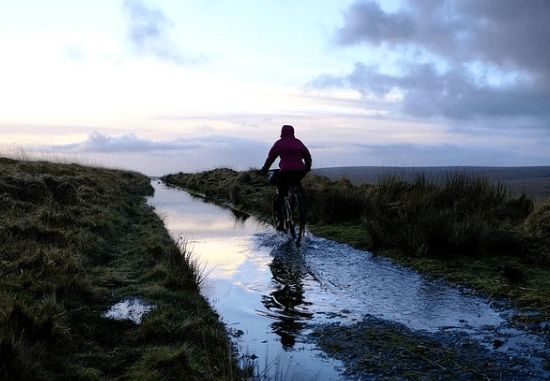 A cyclist riding through a flooded track